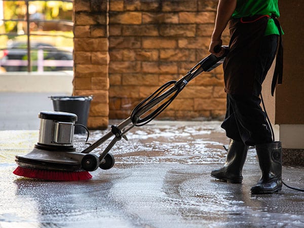 A man worker cleaning the floor with polishing machine