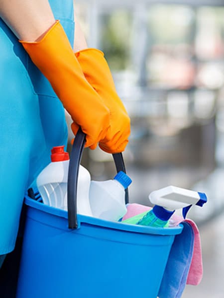 A woman worker in special clothes rolls a trolley for cleaning offices. Cleanroom concept during quarantine.
