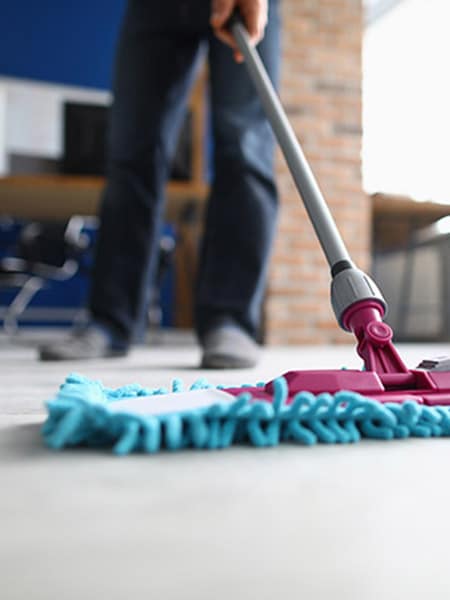 A woman worker in special clothes rolls a trolley for cleaning offices. Cleanroom concept during quarantine.
