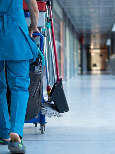 A woman worker in special clothes rolls a trolley for cleaning offices. Cleanroom concept during quarantine.